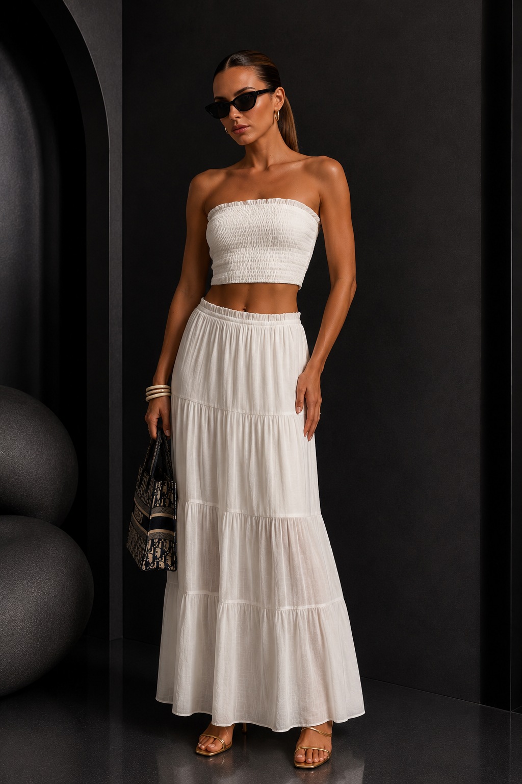 Woman wearing a white strapless top and long skirt against a black background. White Strapless Top &amp; Maxi Skirt Set.