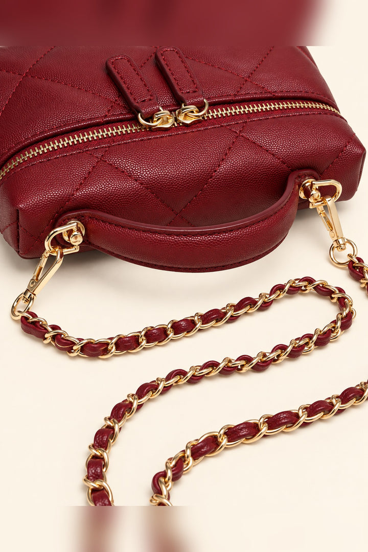 Close detail of the diamond quilting and gold dual zip pulls on the burgundy Snow crossbody
