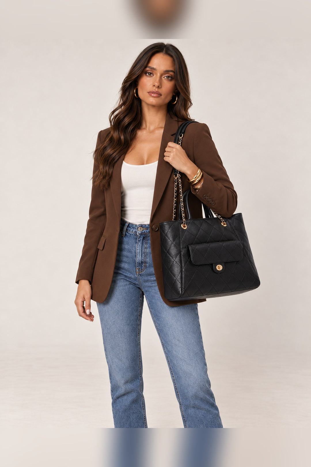 Black quilted Hank tote worn on the shoulder by its chain-accented straps