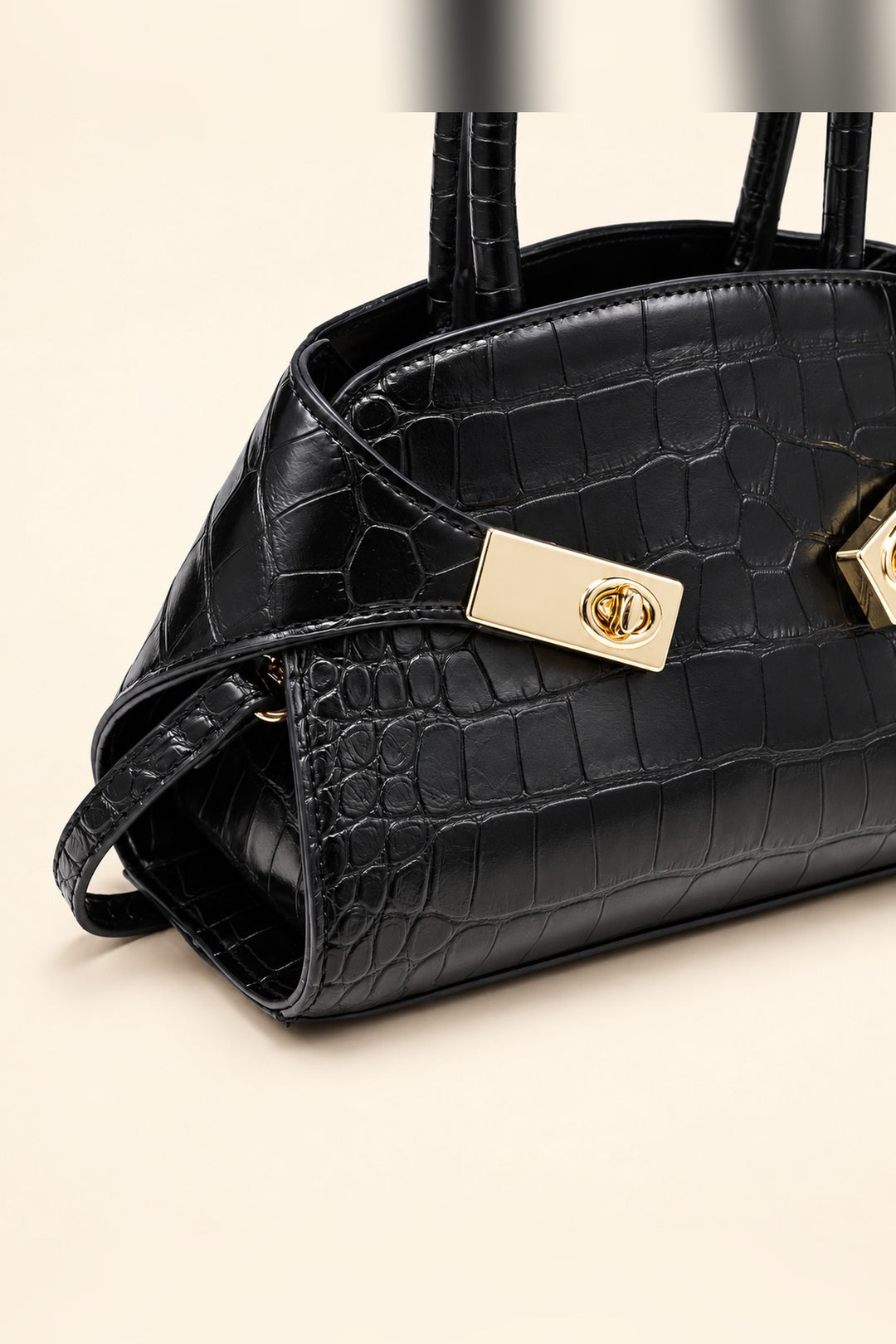 Close detail of the croc texture and gold turn-lock on the black Fable crossbody