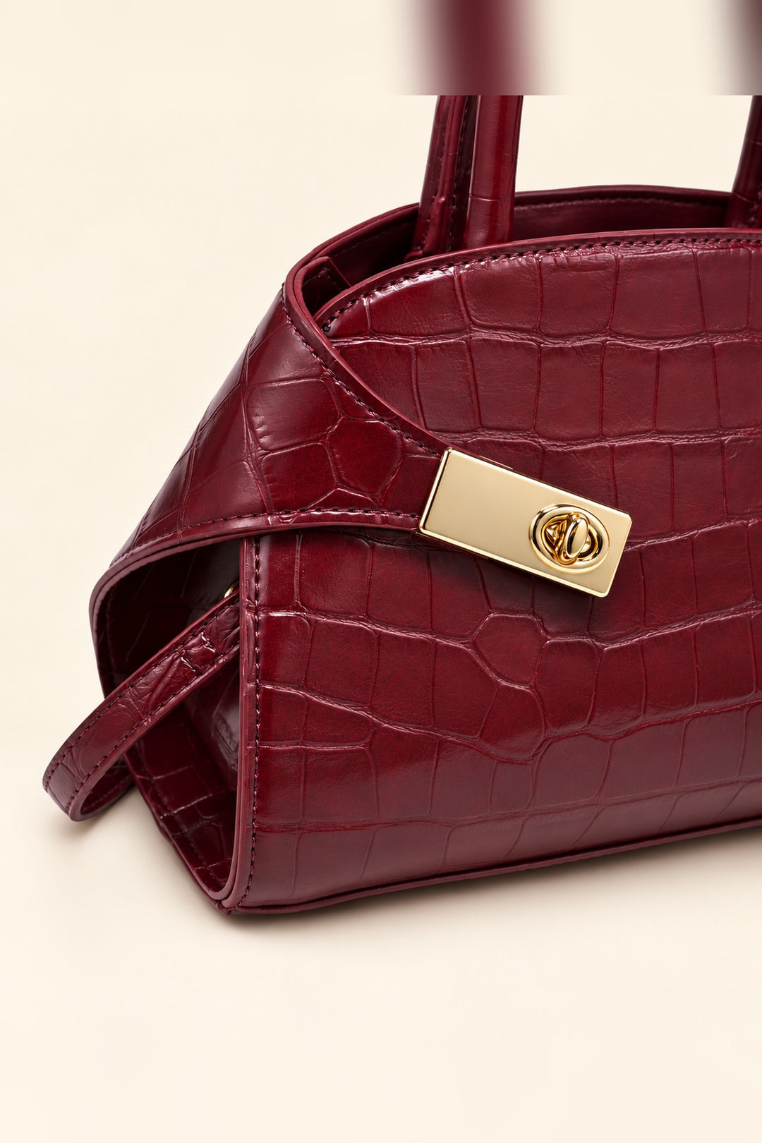 Close detail of the croc texture and gold turn-lock on the burgundy Fable crossbody