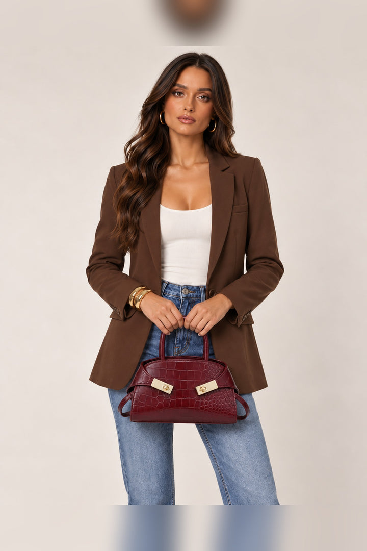 Burgundy croc crossbody carried by its rolled top handles