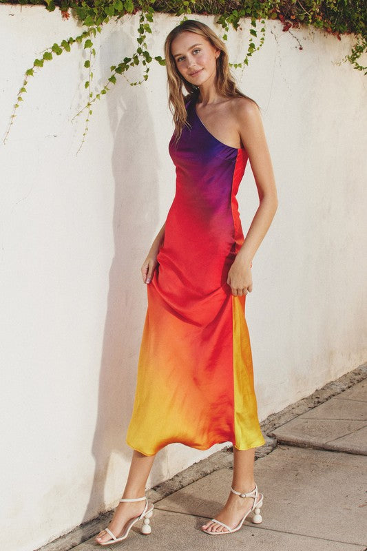 Model is wearing Sunset One Shoulder Maxi Dress with white sandals heels, side view detail of gradient color of the dress 