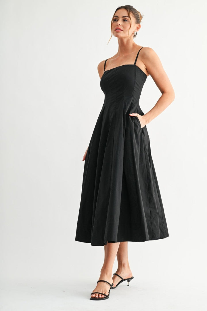 Black A-line midi dress with paneled bodice, hand in pocket