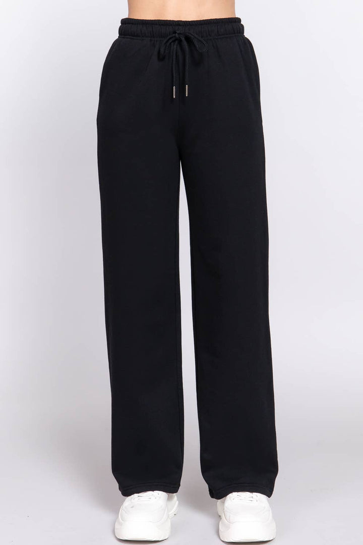 Front view of the black fleece lined straight leg sweatpants with elastic waist and white sneakers