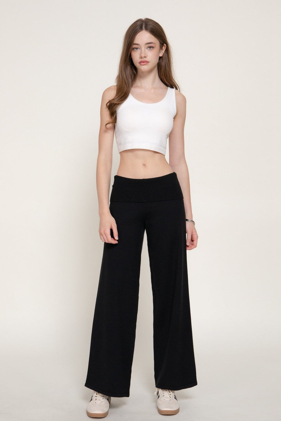 Front view of the black fold over waistband wide leg sweater pants with a white tank top