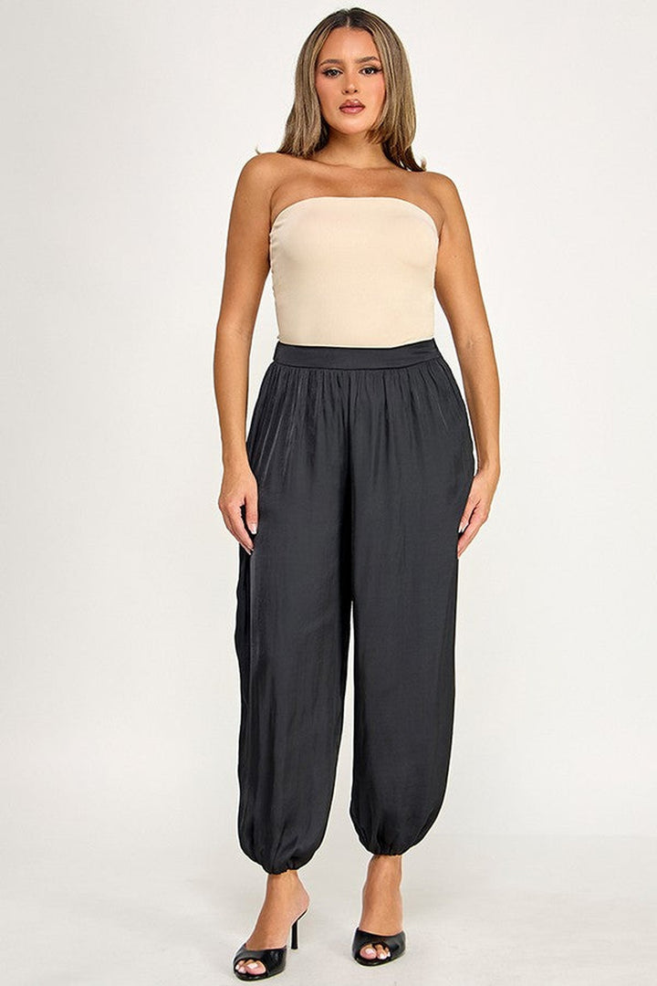 Black satin balloon pants with gathered ankles styled with a cream tube top, front view