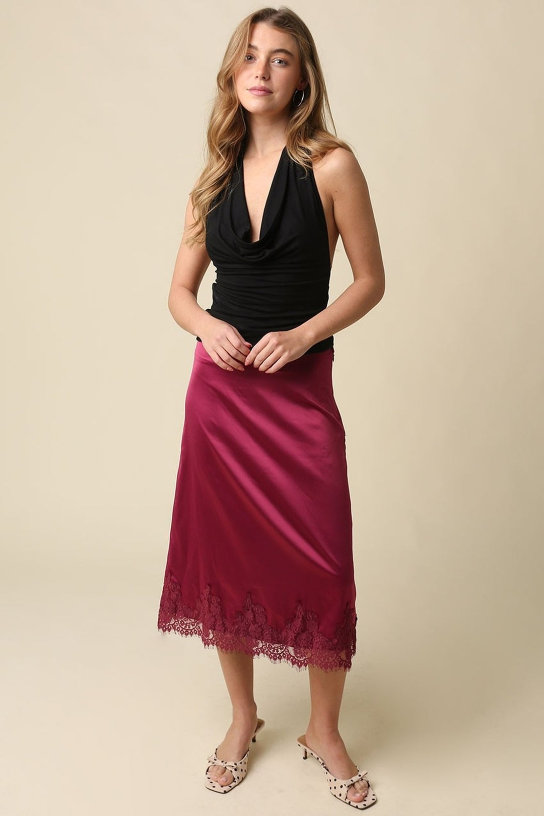 Black cowl neck open back halter top worn with a skirt, full length