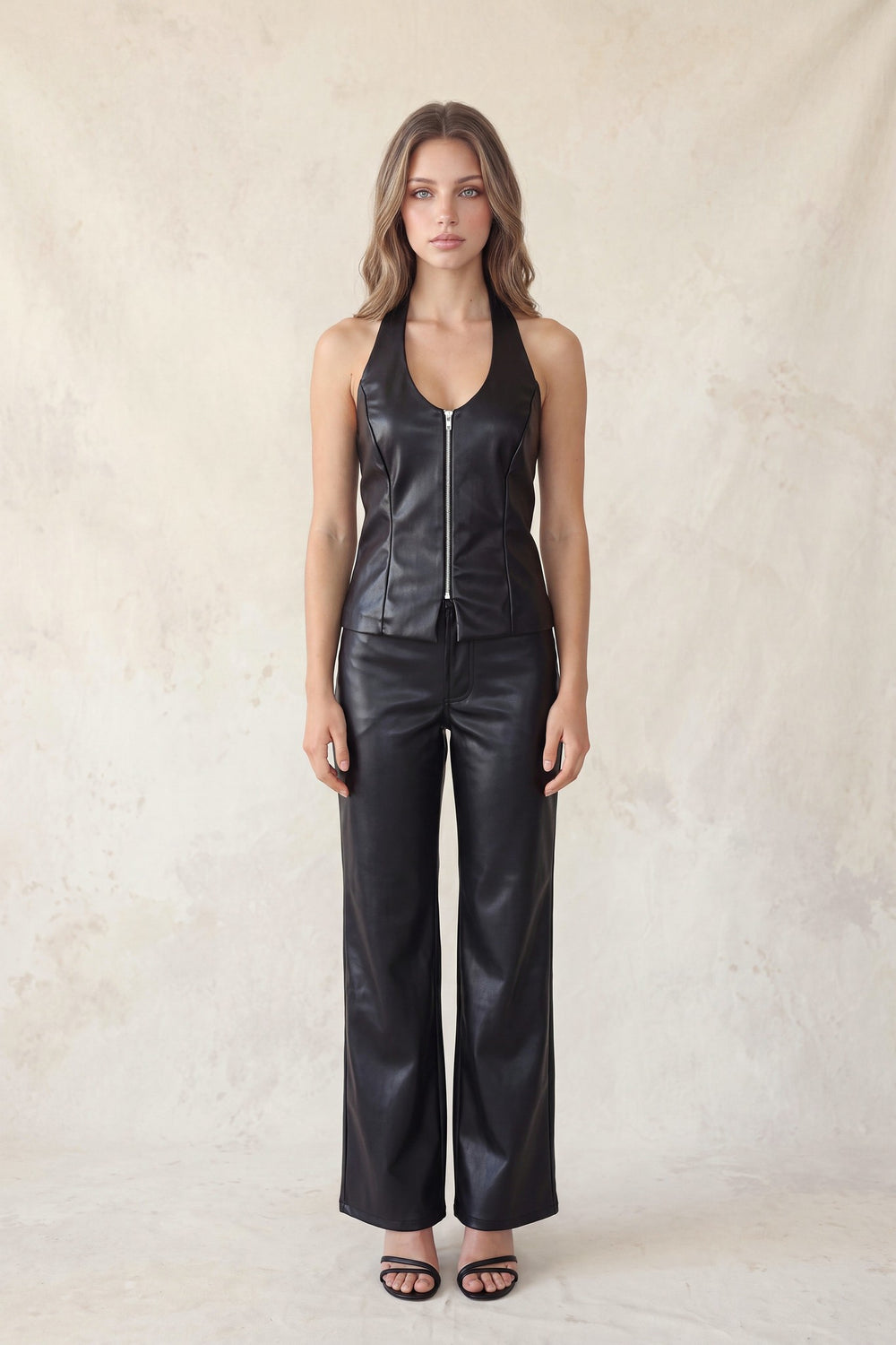 Black faux leather pants styled with a black halter top, full length