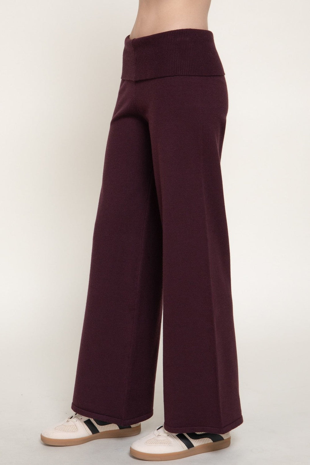 Back view of the burgundy wide leg knit pants with fold over waistband and sneakers