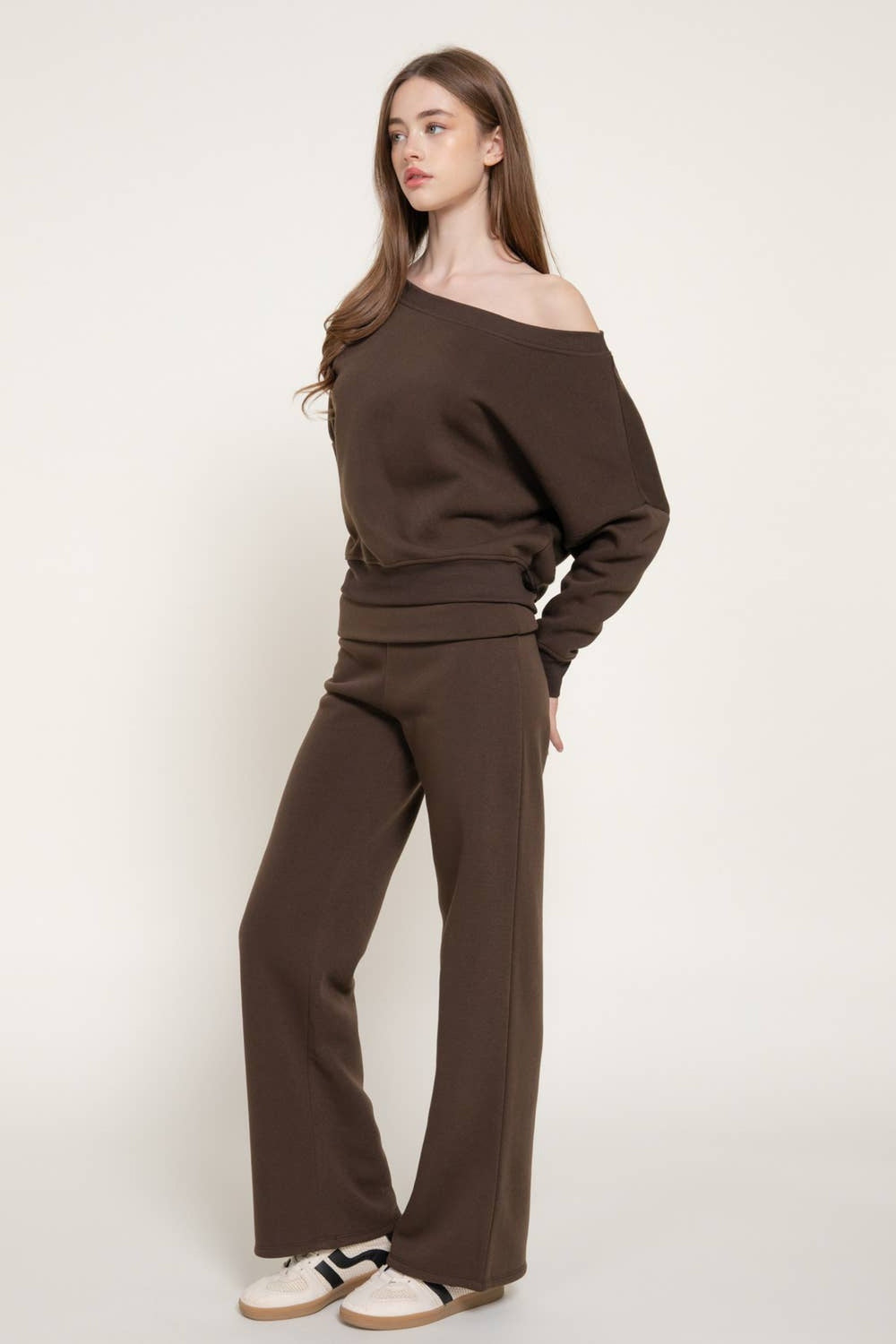 Side view of the chocolate brown asymmetrical neck sweatshirt and wide leg sweat pants set with sneakers