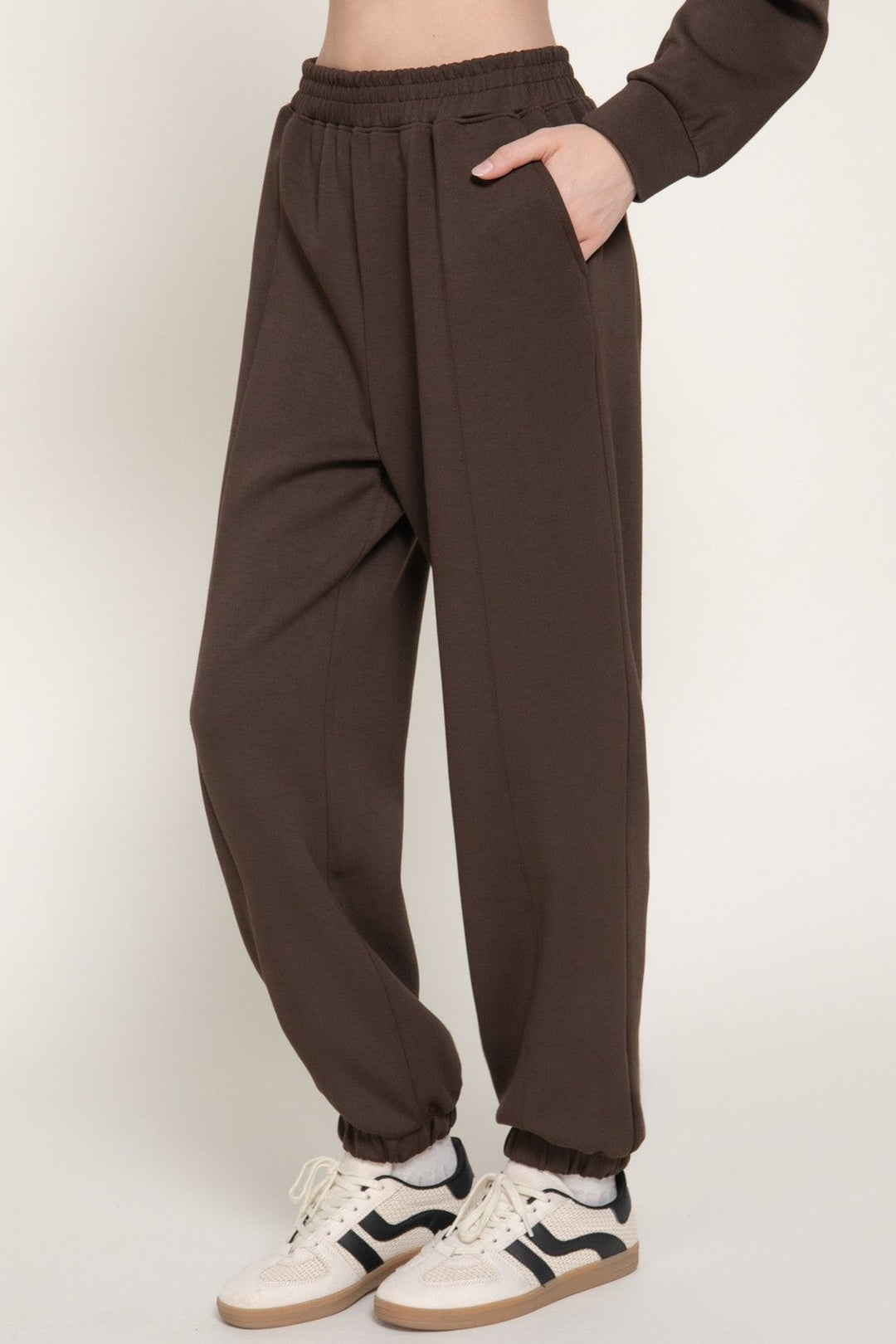 Close up of the pintuck seam and side pocket on the dark brown joggers