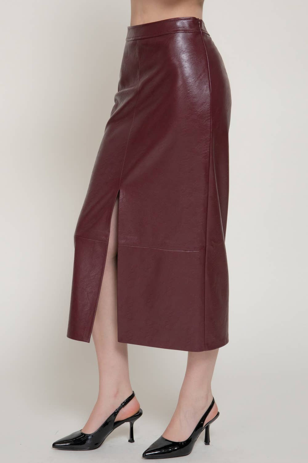 Front view of the ember wine textured faux leather pencil midi skirt with front slit and slingback heels
