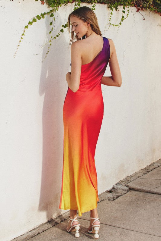 Model is wearing Sunset One Shoulder Maxi Dress  showing the back of the dress and wearing white heels sandals