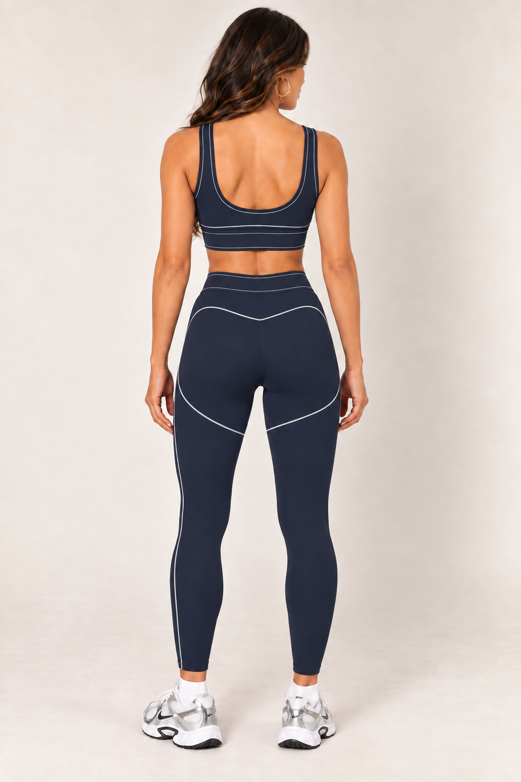 Back view of dark navy contrast thread sports bra paired with matching contour leggings and Nike sneakers.