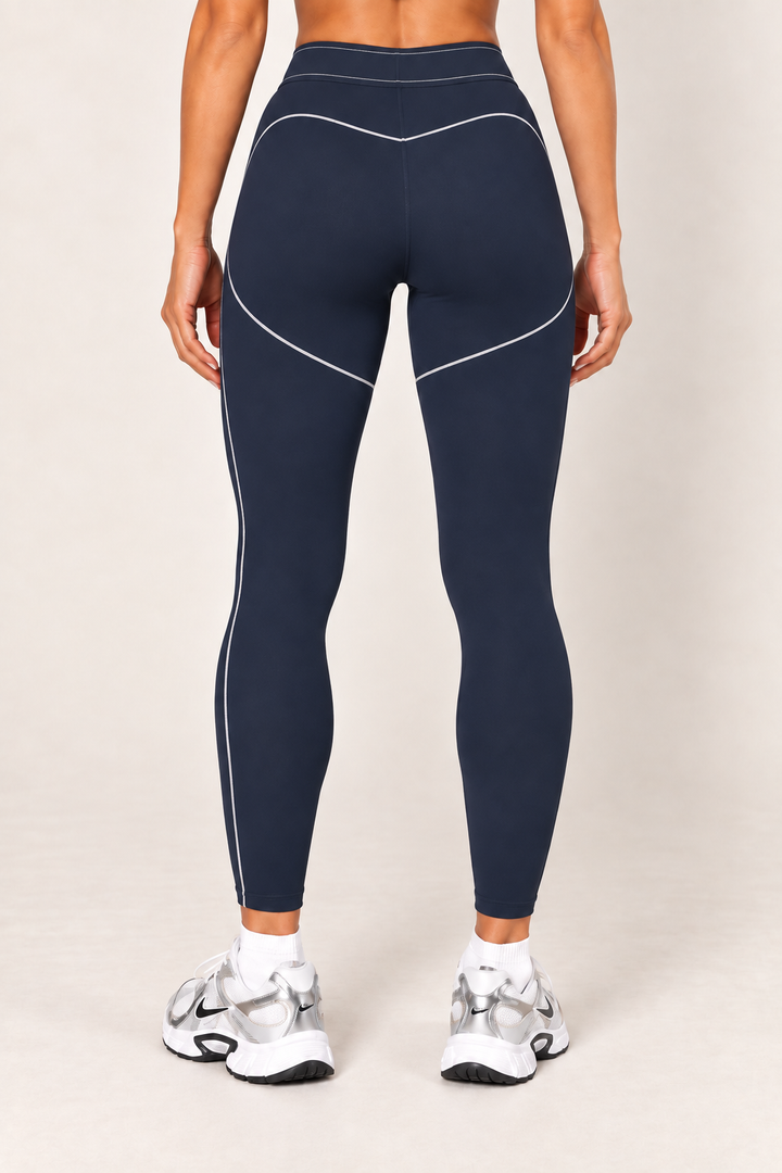 Waist-down back view of dark navy high-rise contour leggings showing the contrast-stitched waistband, curved rear seams and fitted ankle-length silhouette.