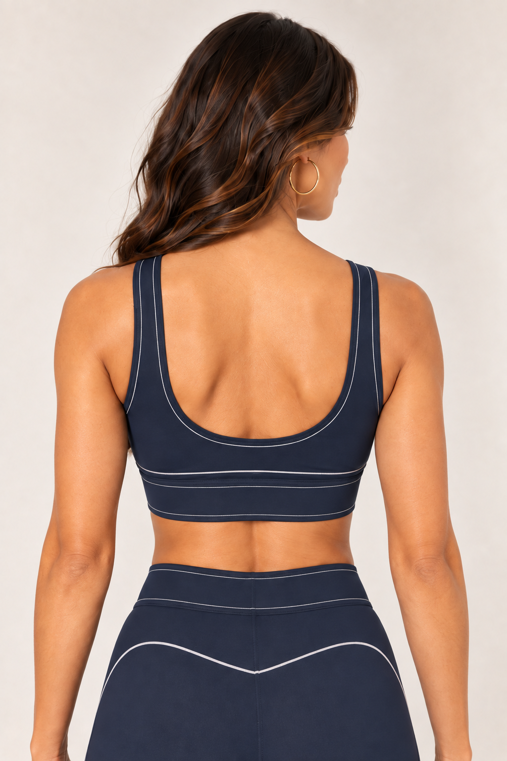 Back close-up of a dark navy sports bra showing the scoop neckline, wide straps and light stitching along the back and underband.