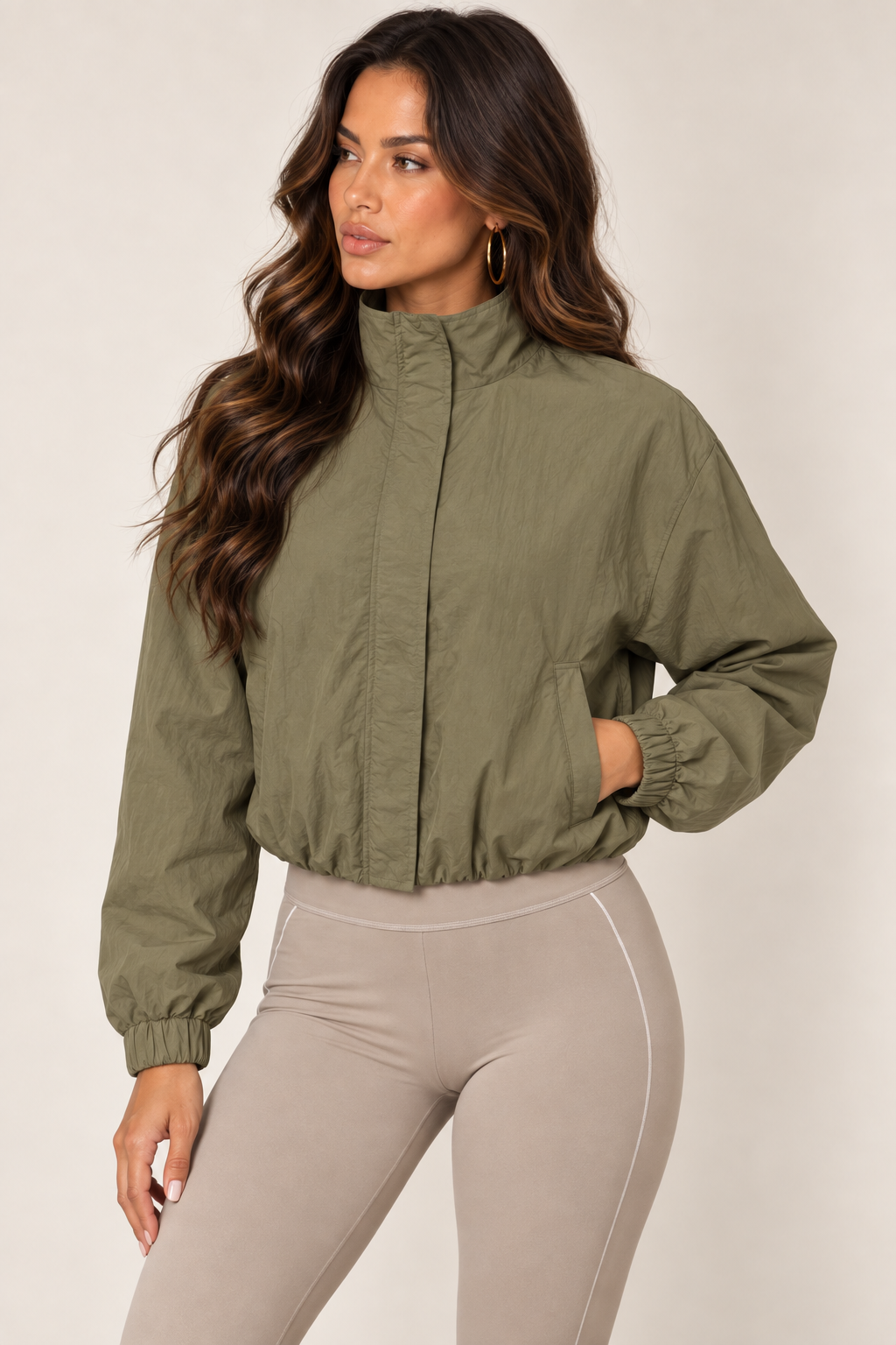 Olive cropped windbreaker with taupe leggings — thigh up left zipped