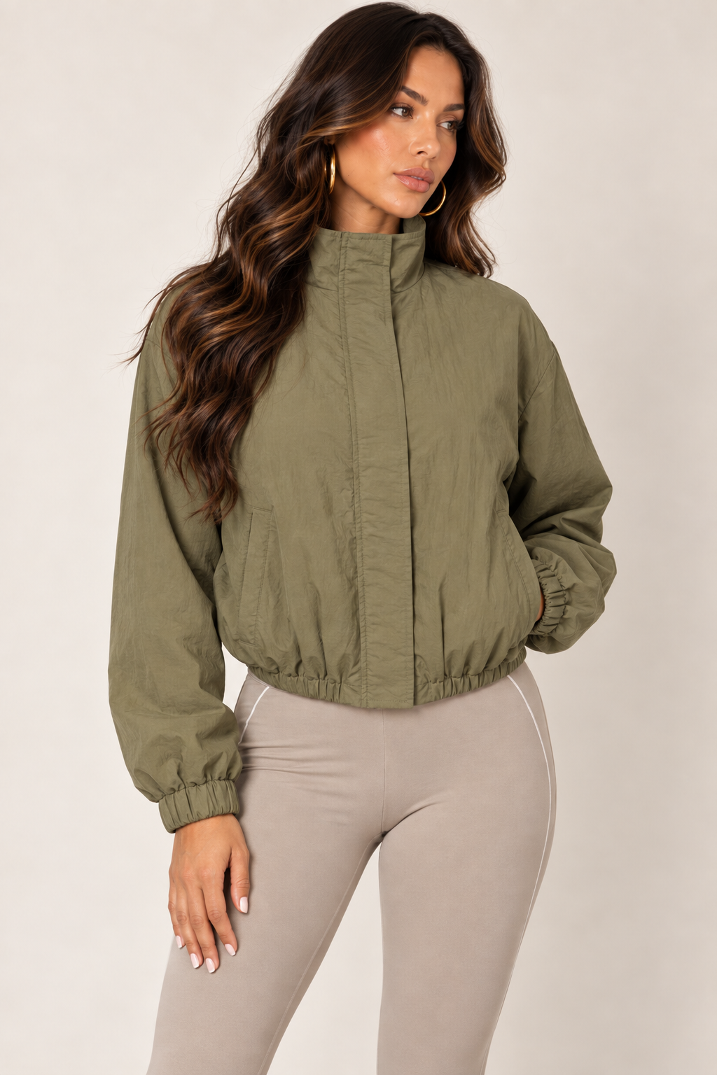 Olive cropped windbreaker with taupe leggings — thigh up right zipped