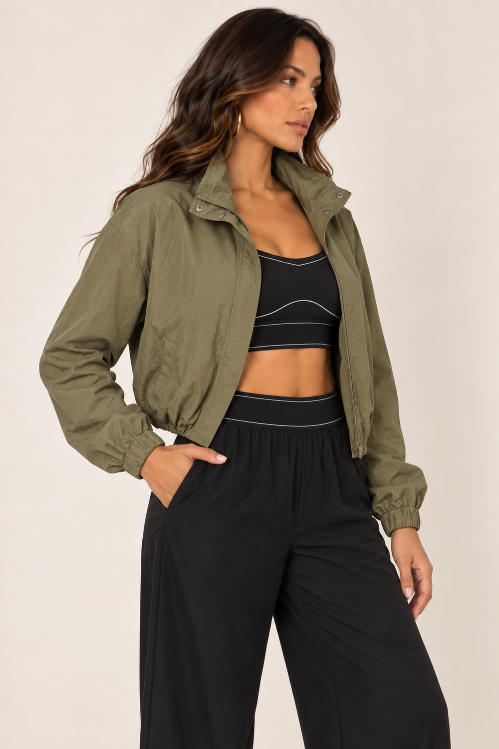 Olive cropped windbreaker with black track pants — thigh up right open