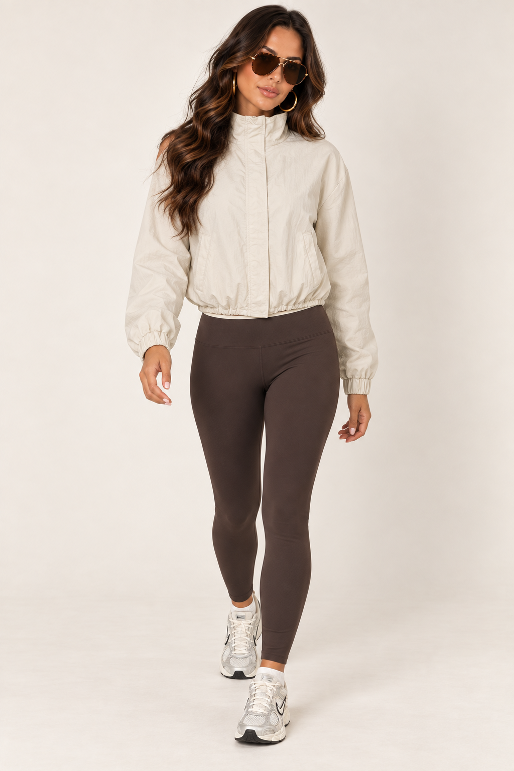 Cream LOVE TREE windbreaker with a chocolate brown athletic tank and leggings, tortoiseshell aviators and white-silver Nike sneakers; full outfit, fully zipped.