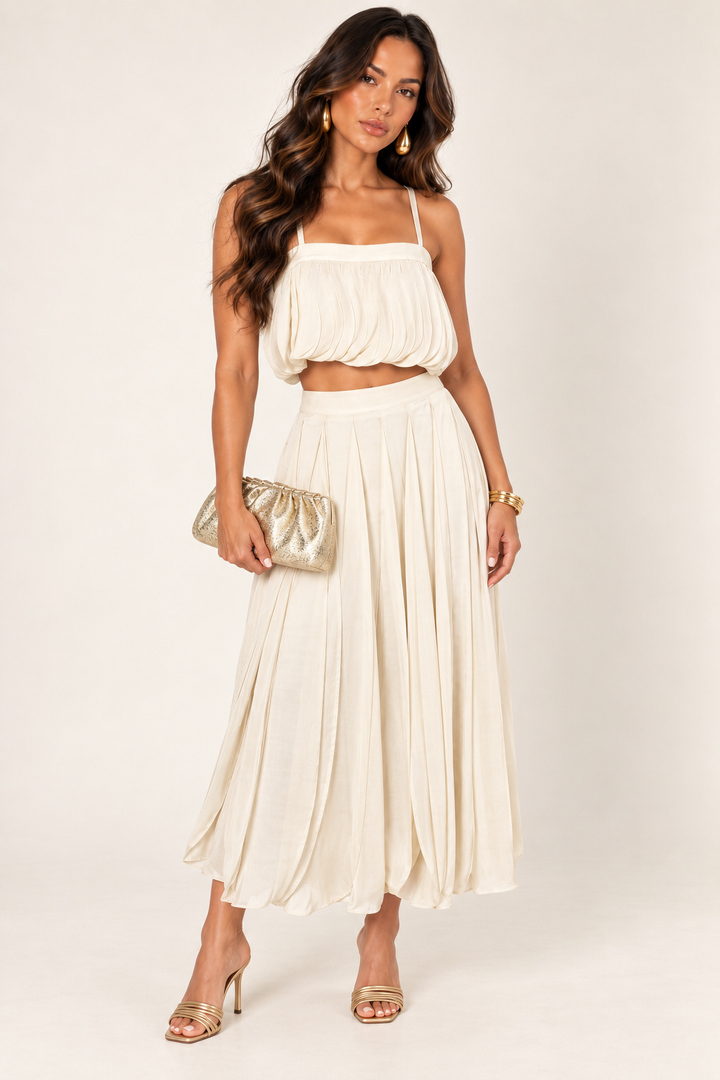 ALX hair-down model wearing sand petal layer skirt set styled with the gold ruched clutch