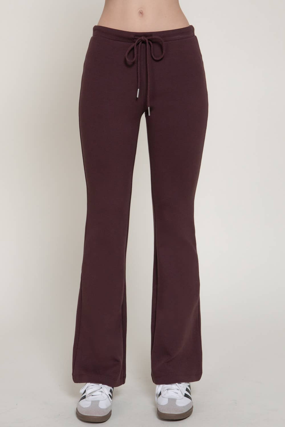 Front view of the maroon flare knit pants with drawstring waist and white sneakers