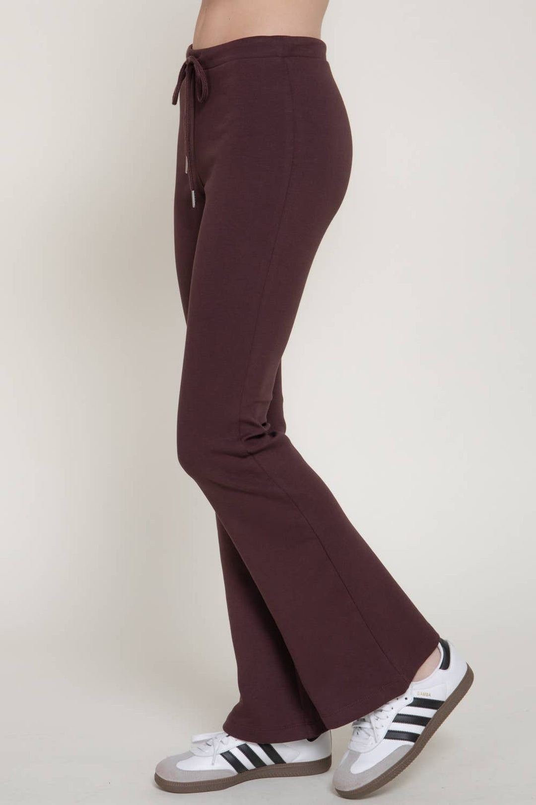 Side view of the maroon flare knit pants showing the fitted hip and flared hem