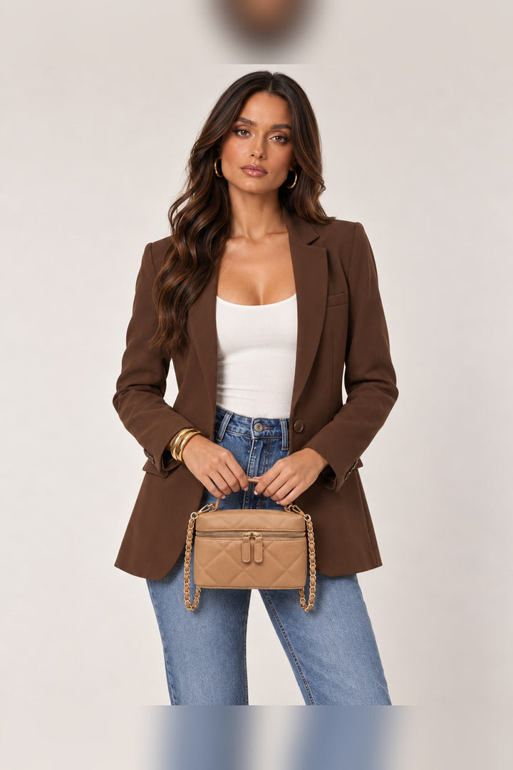 Model carrying the natural tan quilted bag by its top handle, a holiday party accessory