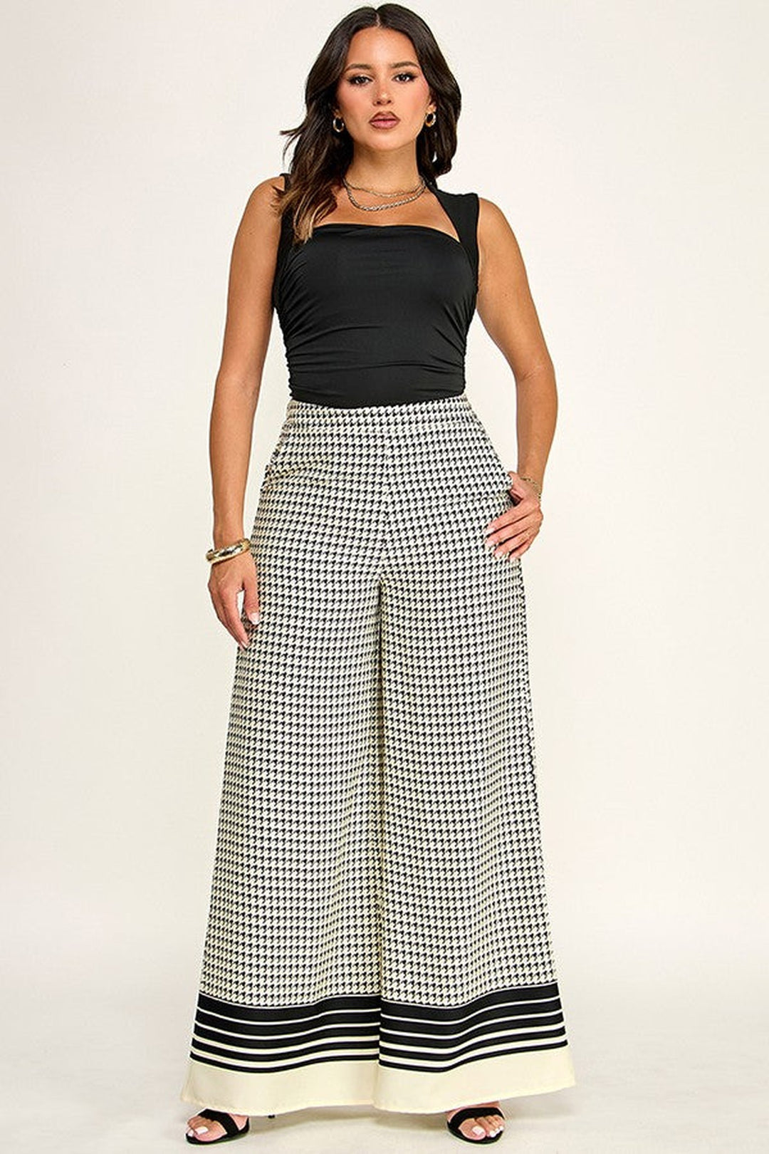Off white and black checkered palazzo pants worn with a black top, full length front view