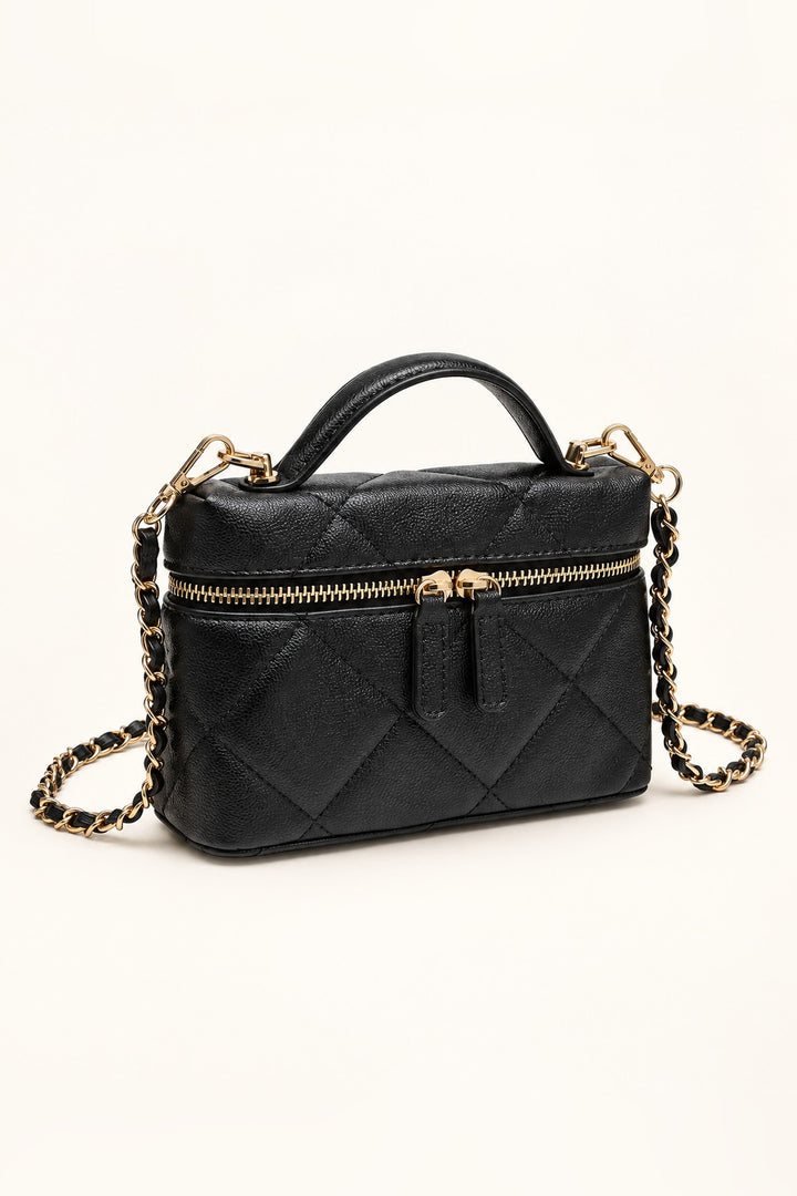 Angled view of the black quilted crossbody bag showing gold-tone double zipper and structured shape