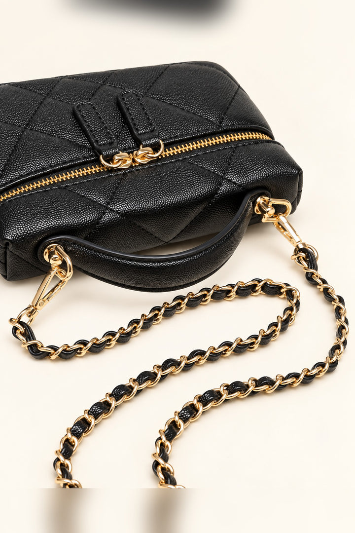 Close-up of the gold-tone zipper pulls and diamond quilting on the black crossbody bag