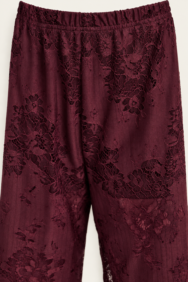 Product-only close-up of the Burgundy Satin Lace Pants Set trousers at Styled by ALX, showing the gathered elastic waistband, seams and tonal floral lace pattern across the upper legs. Deep wine fabric and fine threadwork are photographed against ivory to reveal texture and construction.