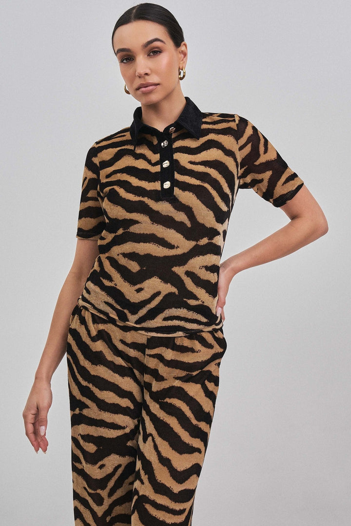 Zebra print knit polo top with black contrast collar and button placket, three-quarter view