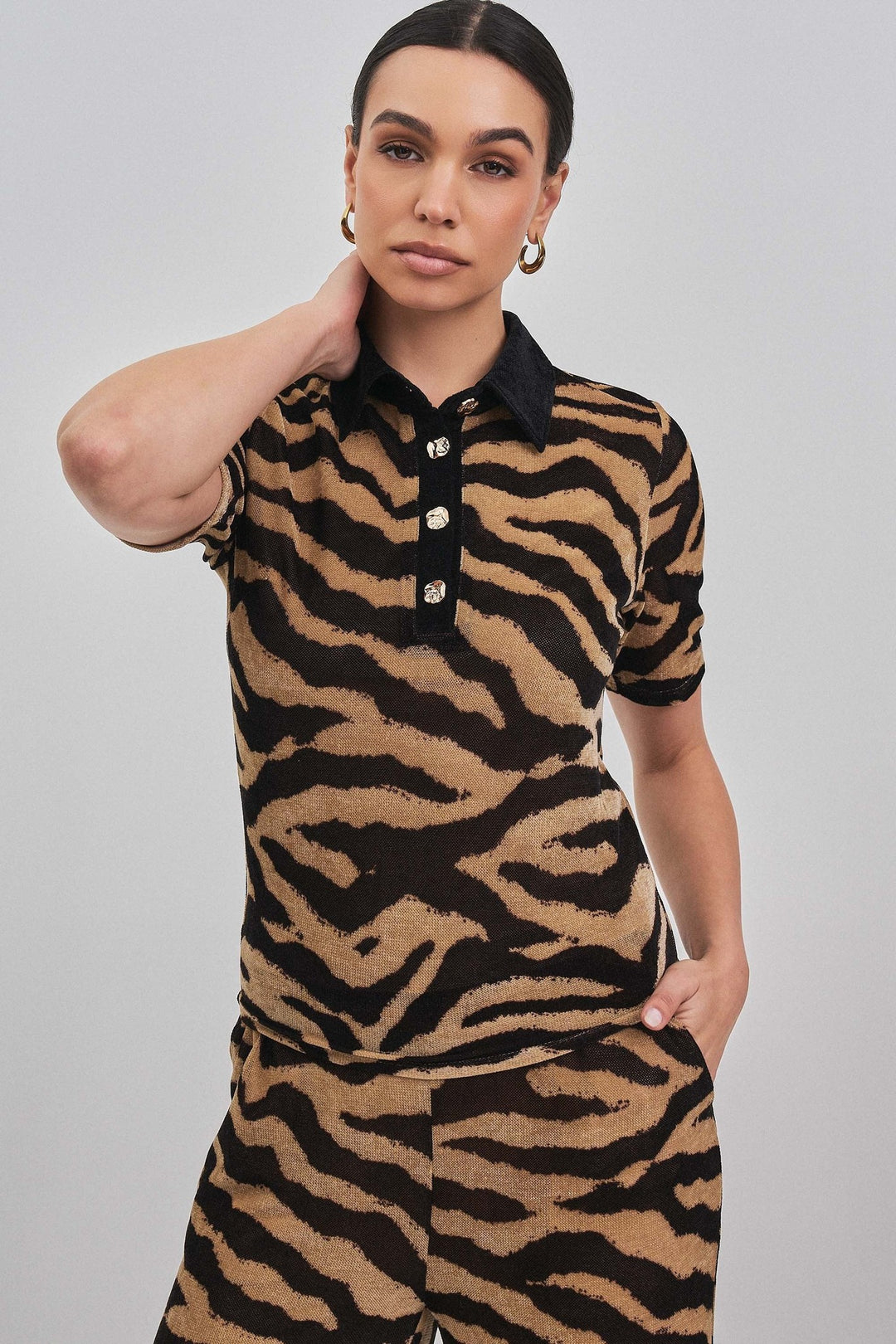 Close up of the black contrast collar and buttons on the zebra print polo top