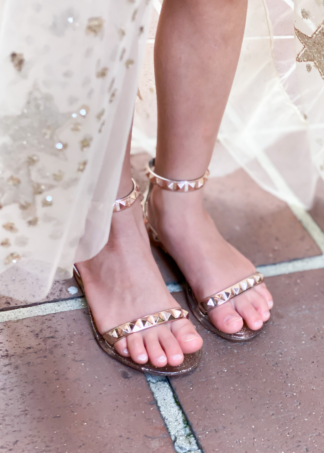 Aria Kids rose gold jelly sandals with studded thin strap across the toes and thin ankle strap. SANDALS FOR BEACH OR POOL DAYS. JELLY SANDALS FOR KIDS. ROSE GOLD JELLY SANDALS