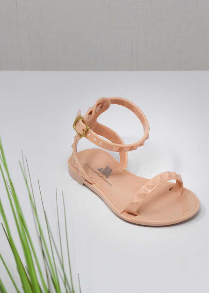 Aria Kids nude jelly sandal with a thin strap across the toes and a thin strap around the ankle perfect for beach and pool days. you can wear them with casual wear with a chic look