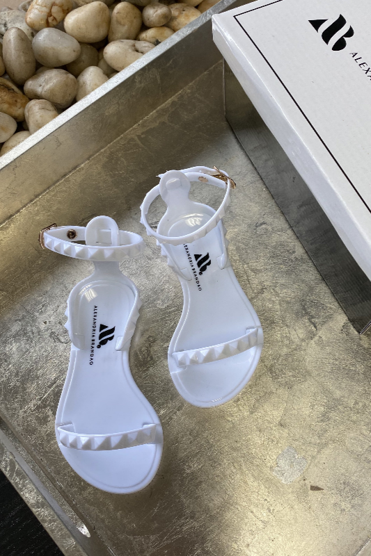 Aria Kids white jelly sandals with studded strap across the toes and thin ankle strap.